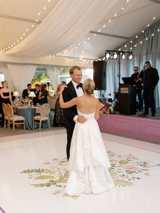 Couple dancing on a floral-bordered dance floor wrap at a tented reception at The Vanlandingham Estate