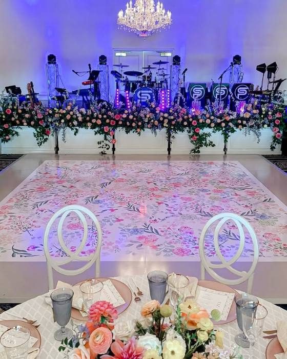 Floral-pattern dance floor wrap in front of a live band stage at The Peninsula Club