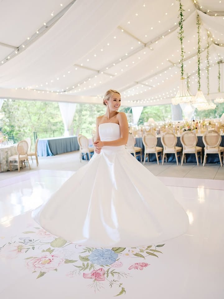Bride standing on a custom floral dance floor wrap under a tented wedding reception at The Vanlandingham Estate